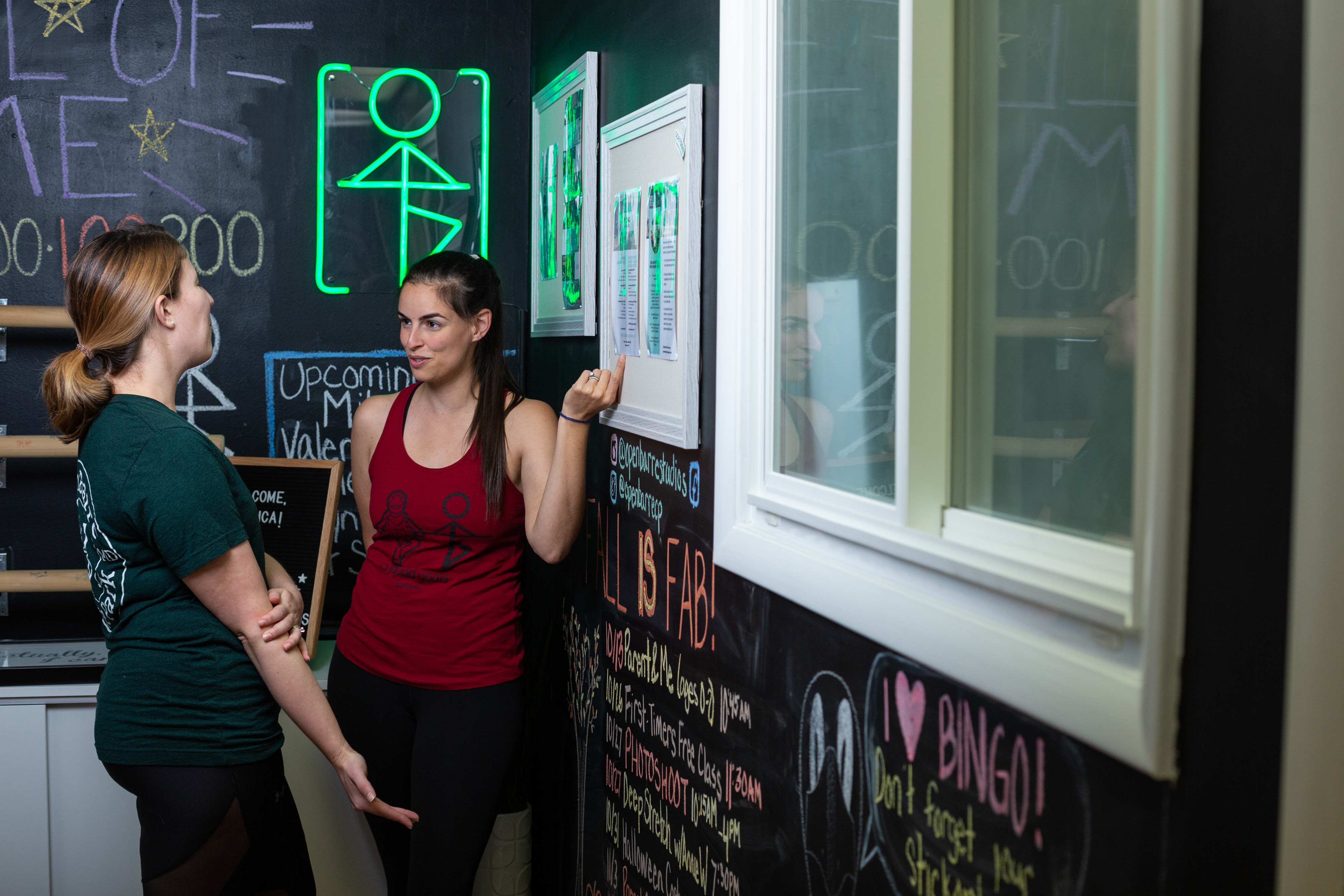 women chatting about fitness classes in barre workout studio with instructor